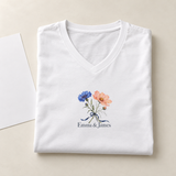 Illustrative folded shirt scene of one white personalized V-neck tee. Emma & James are examples; printed flowers are fixed; props not included.