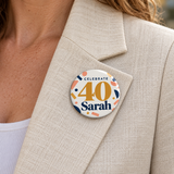 Illustrative jacket lapel scene of one 2.25 inch birthday pin button. Sarah and 40 are personalized examples; clothing, bags, wrapping and props not included.