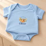Illustrative close-up of the light blue bodysuit with original acorn print and example name Oliver; printed design, not embroidery.